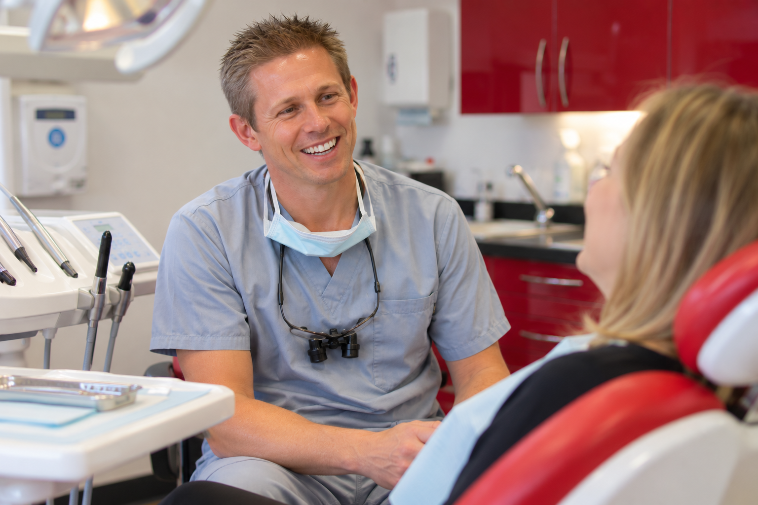 Dr Ross Cutts, his mask pulled down, smiling as he talks with a patient in the dental chair