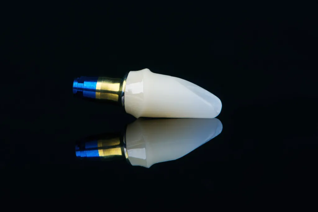 An implant abutment and ceramic crown, photographed close up on black