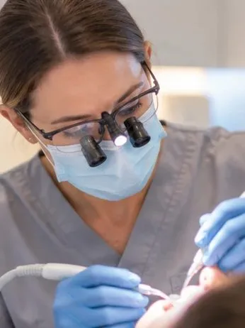 Clinician wearing loupes and a mask at work
