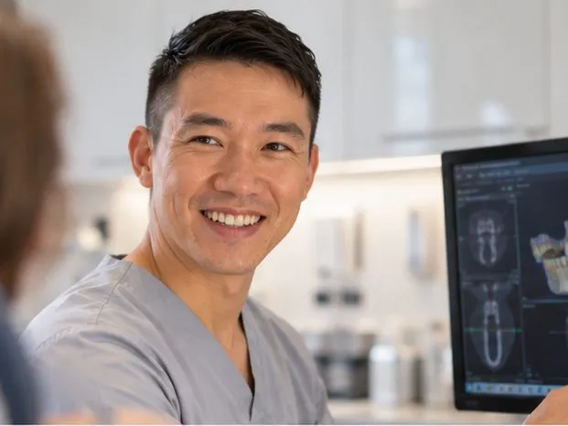 Dr Gavin Ho Fat pointing to a 3D CBCT scan on screen