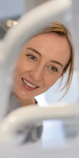 Smiling dentist seen past the dental lamp