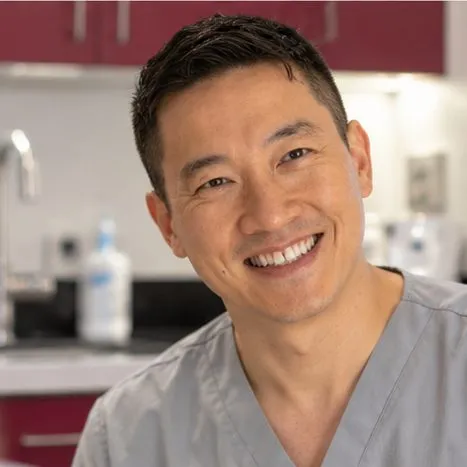 Dr Gavin Ho Fat smiling, with a 3D design of teeth on screen
