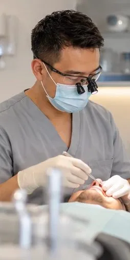 Dentist treating a patient, wearing loupes