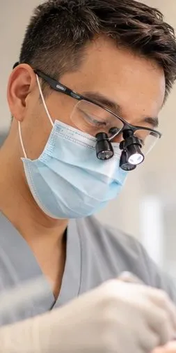 Dentist wearing loupes and a mask during treatment