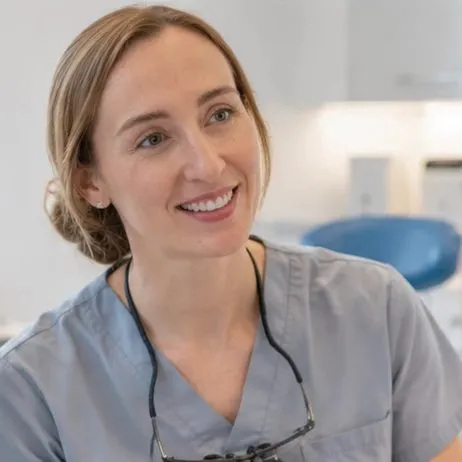 Dentist wearing magnifying loupes, smiling at a patient