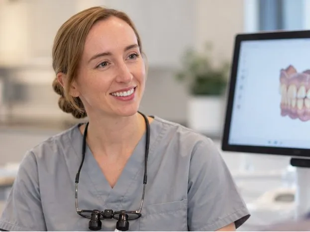 Dr Melanie Bennett smiling with a patient, with a digital design of teeth on screen