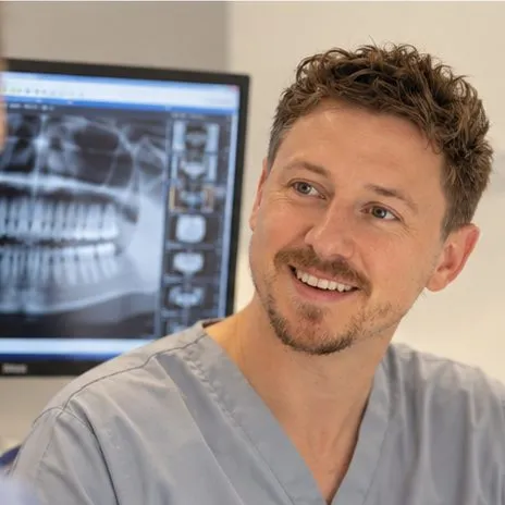 Dr Mark Burton talking with a patient, with an X-ray on the screen behind