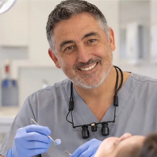 Dr Adrian Jones wearing magnifying loupes, treating a patient