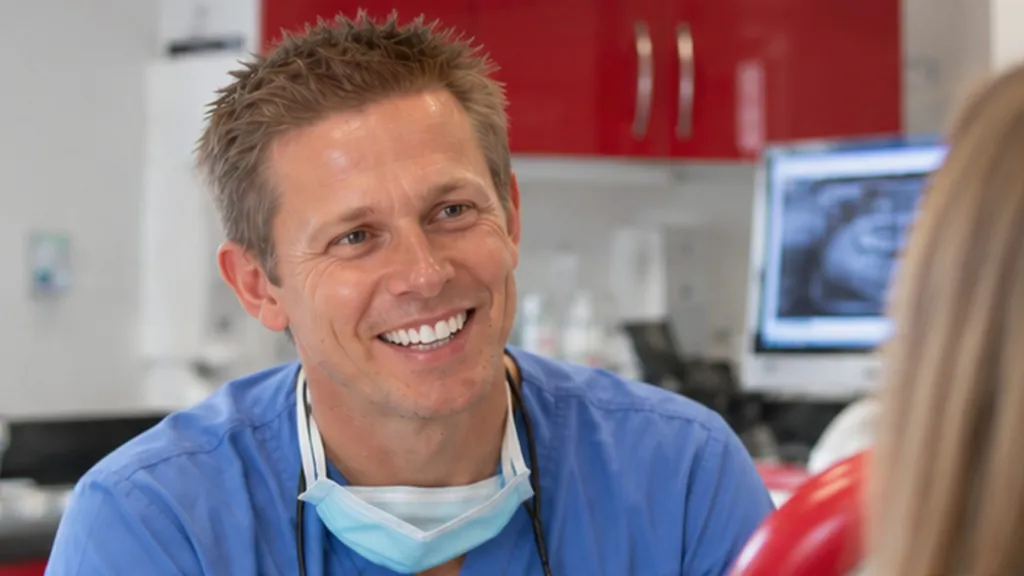 Dr Ross Cutts smiling in his surgery, with an X-ray on the screen behind him