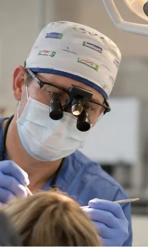 Dr Ross Cutts in a surgical cap and loupes during treatment
