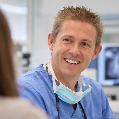 Dr Ross Cutts smiling beside an X-ray on screen