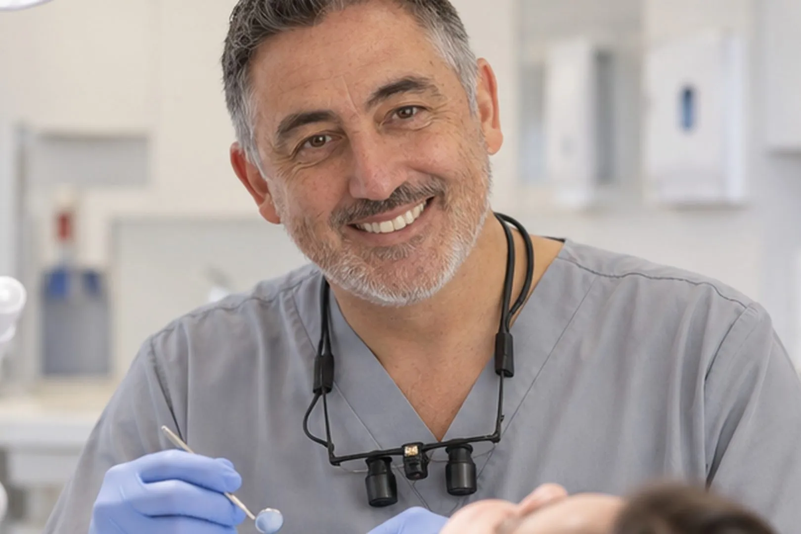 Implant dentist with magnifying loupes, smiling